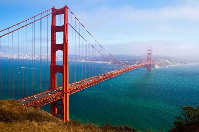 114083809 featured image Red suspension bridge over blue water with city background