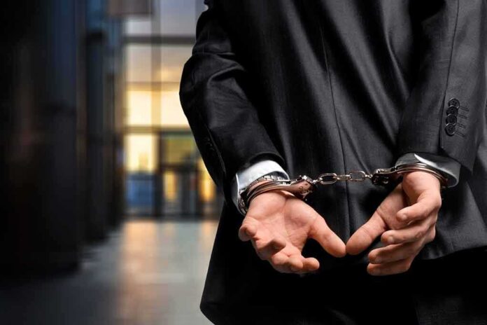 1182595936 featured image Person in handcuffs wearing a suit in office.