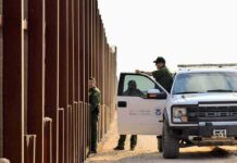 Border patrol agents near a tall metal fence
