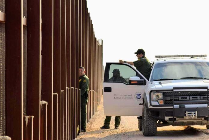 1545833798 featured image Border patrol agents near a tall metal fence