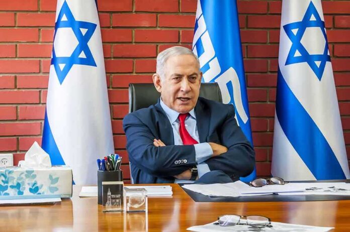 1564752907 featured image Man sitting at desk with Israeli flags behind