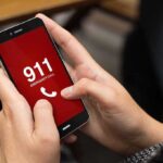 Person holding smartphone with 911 emergency call screen