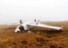 Overturned crashed airplane on grassy field