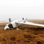 Overturned crashed airplane on grassy field