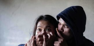 Man holding womans mouth gesturing silence