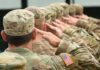 Soldiers in uniform saluting American flag patch visible