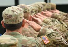 Soldiers in uniform saluting American flag patch visible