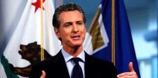 Man speaking with flags in the background