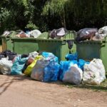 Overflowing garbage bins with bags on the ground