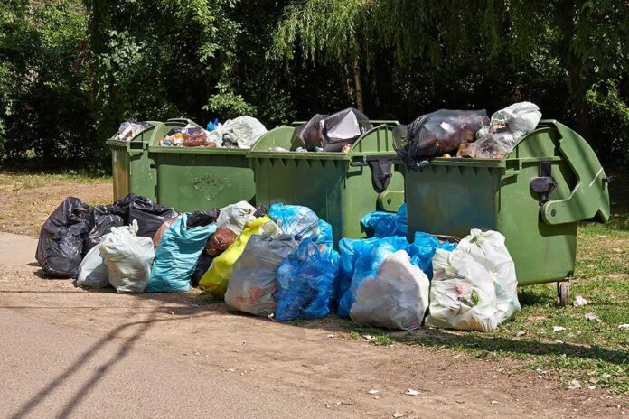 Overflowing garbage bins with bags on the ground