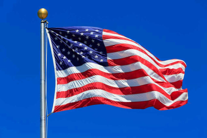 442392457 American flag waving against a clear blue sky