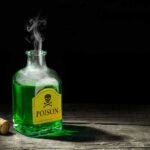 Green poison bottle with cork on wooden surface
