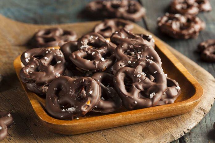 A wooden bowl filled with chocolate-covered pretzels sprinkled with sea salt