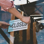 Retailer COLLAPSES — All 1,325 Stores CLOSING Hand placing closed sign on glass door
