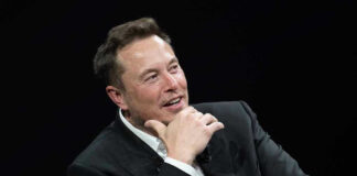 Man in suit smiling, resting chin on hand