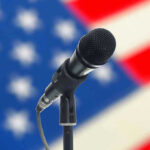 Microphone in front of blurred American flag background.