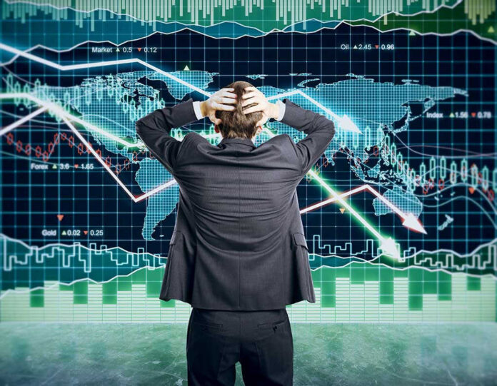 Person in front of falling stock market graph.