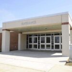 Ex-AOC Staffer ARRESTED for Shocking School Threat Entrance of a modern school building with glass doors and a brick facade