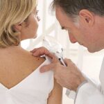 Doctor examining a patient's skin with a magnifying glass