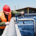 Worker in safety gear inspecting water treatment equipment
