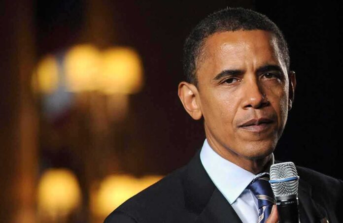 A man in a suit speaking into a microphone with a serious expression