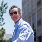 Man in sunglasses wearing a blue button-up shirt.