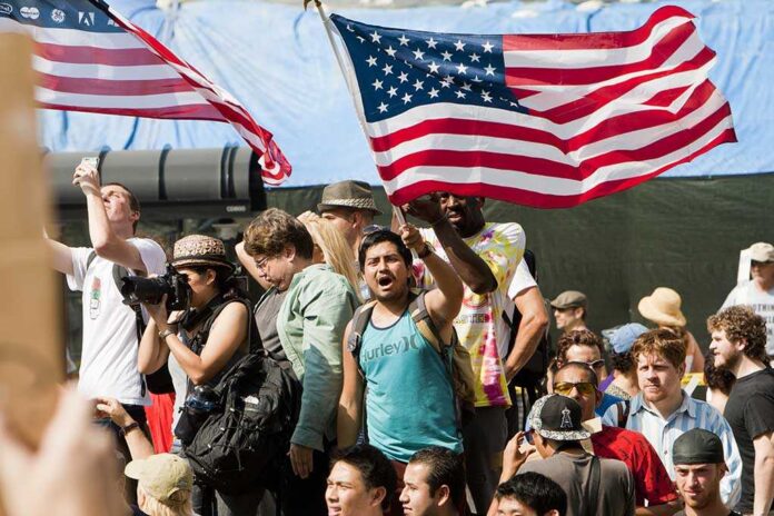 A diverse crowd at a protest holding an American flag