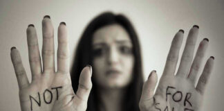 Handcuffed woman shows NOT FOR SALE on her palms.