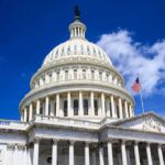 Controversial Flag Invades Federal Buildings – Ignites Fury! The U.S. Capitol building with a dome and American flag against a blue sky
