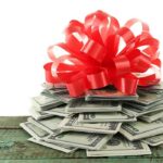 Trump SHOCKS With $1,776 Christmas Handout – See Who Qualifies A stack of cash topped with a red ribbon bow
