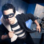 Naked Gunman TERRORIZES Florida Meat Market A masked thief in a striped shirt holding a bag while emerging from a bank vault