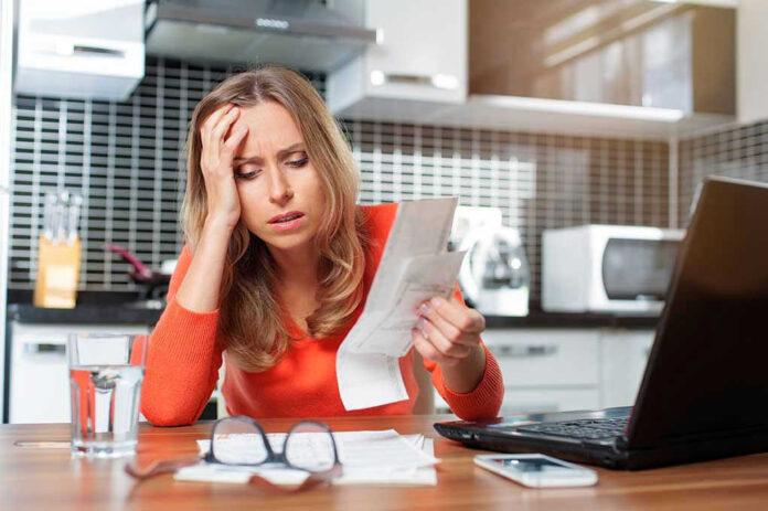 Woman looking stressed holding bills in kitchen
