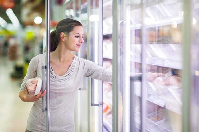 A woman shopping in the frozen food aisle of a supermarket