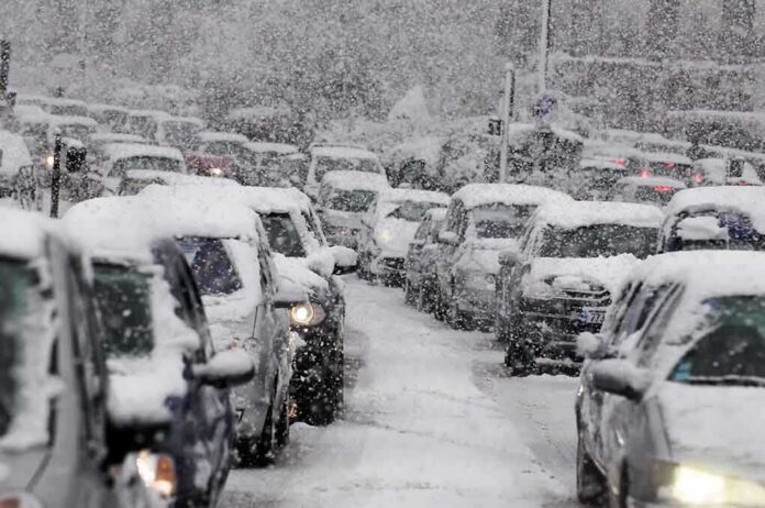 Traffic jam with cars covered in heavy snow during a snowstorm