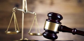 A wooden gavel and scales of justice on a wooden surface