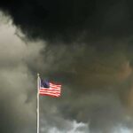 U.S. Drug War EXPOSED: Hidden Motives Revealed American flag waving against a dark, stormy sky