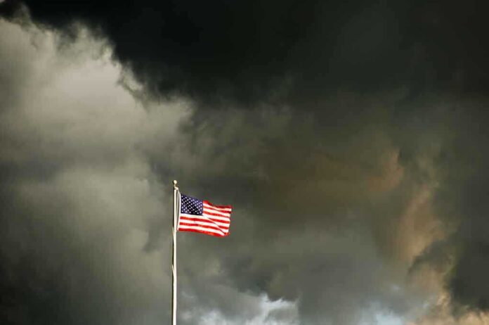 American flag waving against a dark, stormy sky