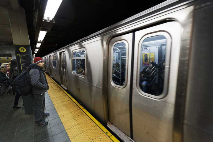 Man waiting at subway platform with departing train.