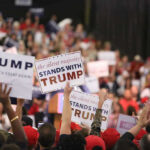 Grammys Roast EXPLODES Into Trump Drama Crowd holding signs supporting Trump at a rally.
