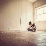 Midlife Crisis? NO, It’s Worse: U.S. Generational Downfall A child sitting alone in an empty room, covering their face with their hands
