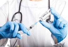 Vaccine Probe SHAKES Up Health Department Doctor filling syringe with vaccine from vial.