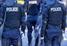 Police officers in riot gear with shields.