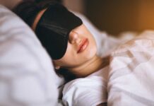 A woman wearing a sleep mask, resting in bed
