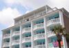 Exterior view of a beachfront hotel with balconies and colorful towels hanging