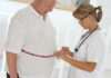 BMI Lie Exposed: Risk Still Rising A healthcare professional measuring a patients waist with a tape measure