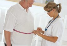 A healthcare professional measuring a patients waist with a tape measure