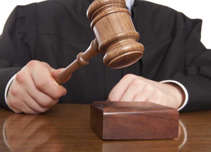 A judge holding a gavel above a wooden block