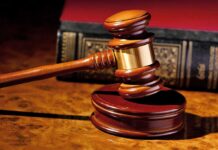 A wooden gavel resting on a polished surface with a law book in the background