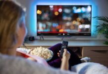 Vince Vaughn’s BRUTAL Truth About Late-Night TV Person sitting on a couch watching a movie on a TV with popcorn in hand