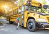 A child with a backpack boarding a yellow school bus